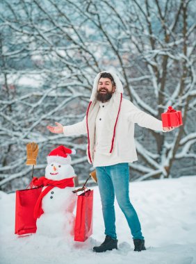 Kış kardan adam geçmişinde Noel hediyesi olan mutlu bir baba. Mutlu Noeller ve mutlu Noeller. Beyaz karlı arka planda Noel Adamı ve Kardan Adam
