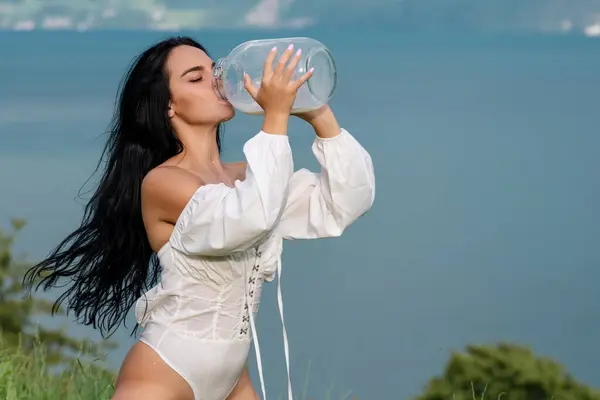 Young woman in lingerie drinking. Woman body with face splashed milks. Young woman drinking milk from bottle. Female mouth with dripping milk. Natural organic milk. Sexy model with splash milk