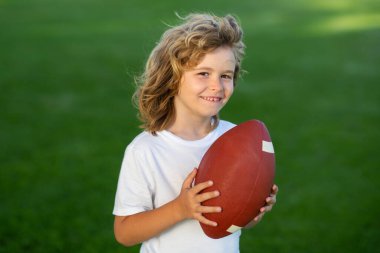 Sporcu çocuk. Futbol, ragbi, Amerikan futbolu. Çocuk dışarıda futbol oynuyor.