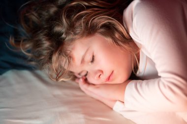 Çocuk yüz üstü uyuyor. Sarışın, beyaz, yatakta uyuyan bir çocuğun güzel yüzü. Tatlı çocuk rüyaları. Küçük çocuk yatakta uyuyor.