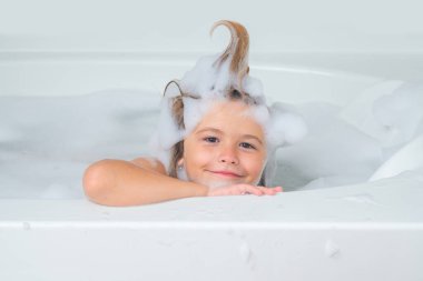 Çocuk şampuanı. Çocuk kafasında köpük. Komik banyo. Çocuk köpükle banyo yapıyor. Banyoda banyo yapan komik çocuk suratı. Komik çocuk suratı