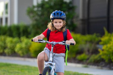 Bisikletli çocuk. Bisiklet süren kasklı bir çocuk. Şehir parkında bisiklet süren kasklı beyaz çocuk. Önce çocuk bisikleti. Çocuk yaz etkinliklerinde. Bisikletli çocuk. Çocuk bisiklete biniyor