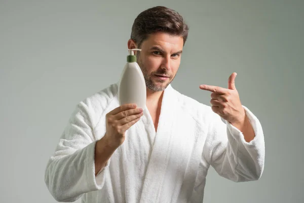 Cosmetics male products. Man with skincare products, beauty product and cosmetics isolated on gray studio background. Advertising with cosmetics bottle, spa marketing. Beauty concept
