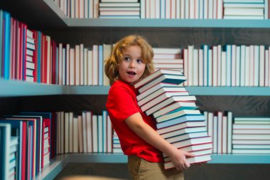 Kütüphanede kitap okuyan bir çocuk. Çocuk gelişimi, okumayı öğrenmek. Öğrenci bir kitapçıda kitap okuyor.