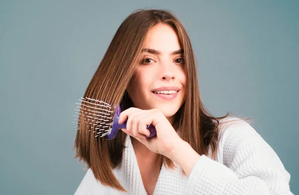 Woman combing hair. Portrait of female model with a comb brushing hair. Girl with hairbrush, hair care and beauty. Close up female face