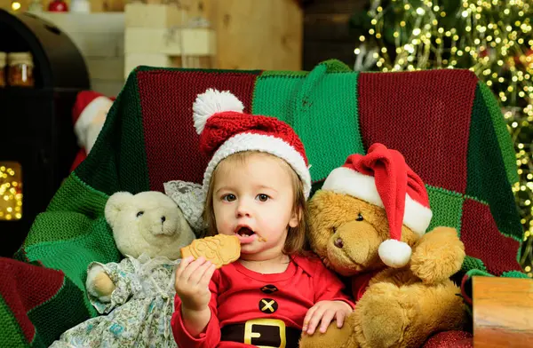 サンタの帽子をかぶった小さな赤ん坊は お菓子を食べる 新年の子供の休日 — ストック写真