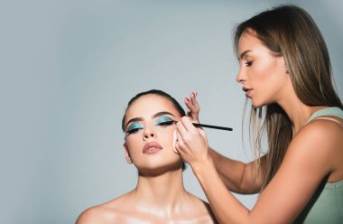 Güzellik makyajı. Makyöz göz farı sürüyor. Vizeci bir el, genç bir güzellik modelinin kozmetik ürünlerini boyuyor. Profesyonel makyaj süreci. Moda ve güzellik, kozmetik, güzellik salonu