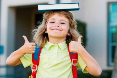 Gözlüklü yakışıklı bir okul çocuğunun portresi ve kitap tutan bir gömlek. Okullu inek öğrenci dışarıda.
