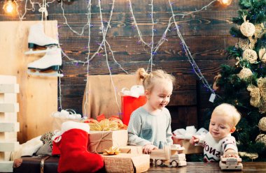 Kışın giyinmiş küçük mutlu çocuk Noel ağacının yanında Noel Baba 'yı düşün. Gülümseyen çocuk Noel ağacının arkasından dikizliyor. Ahşap arka planda Noel hediyesi olan mutlu çocuk.