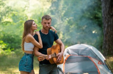 Bahar manzarasında kamp yapan romantik bir çift, gitarlı bir adam. Genç aşıklar için doğa kampçıları macerası. Birbirine aşık yürüyüş yapan çift.