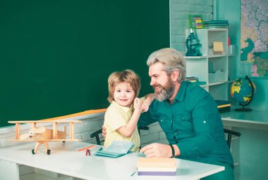 İlkokul öğrencisi içeride okuyor. İlkokul öğretmeni. İlkokul. Babası tahtada eğlenen komik küçük bir çocuk.