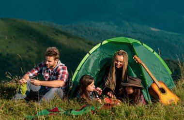 Kamp gezisindeki gençler. Sağlıklı yaşam tarzı ve eko turizm. Bir grup mutlu arkadaş çadırda yaz meyvelerini yiyorlar.