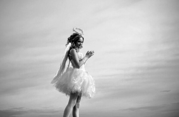 Charming curly little girl in white dress and wings - angel cupid girl. Enjoying magic moment. Teenager Cherub Cupid. Heaven