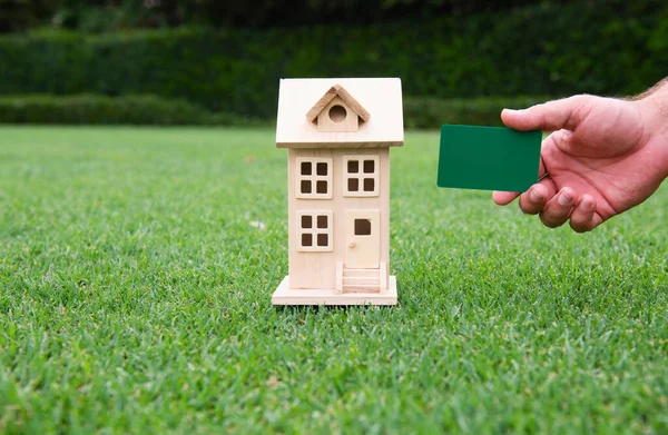 Symbols of real estate investors, taking care of credit and contracts. Toy house and credit card in hands
