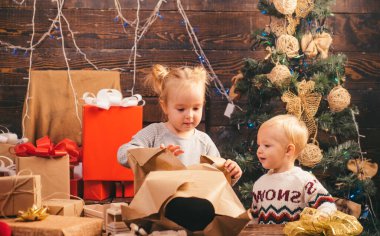 Çocuk kapalı Noel ağacı yakınındaki eğleniyor. Mutlu bir Noel hediye ile Noel Baba şapkalı küçük çocuk sahibi. Mutlu Noeller ve mutlu tatiller. Çocuk hediye. Kış akşam evde
