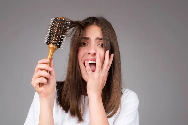 Young woman with hair loss problem worried about hairloss. Messy bed hair. Problem with tangled hair. Worried girl with damaged hair. Hairloss problem. Portrait of woman with a comb and bad hairs