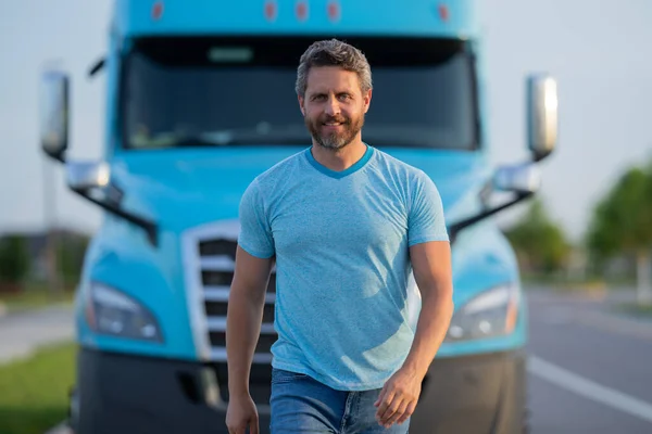 Men driver near lorry truck. Man owner truck driver in t-shirt near truck. Handsome middle aged man trucker trucking owner. Semi trailer, semi trucks. Handsome man posing in front of truck