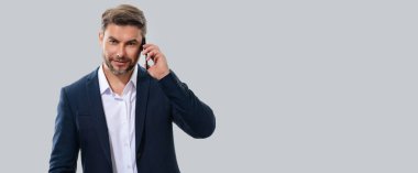 Takım elbiseli yakışıklı bir adamın portresi akıllı telefon kullanıyor, sohbet ediyor, sosyal medyada mesaj yazıyor. Telefondaki iş adamı araması stüdyo geçmişinden izole edilmiş. Başlık için pankart, kopyalama alanı