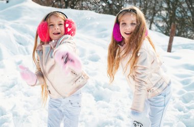 Snowball fight. Winter kids having fun playing in snow. Kids throwing a snowball. Two little girl playing on snow in winter time