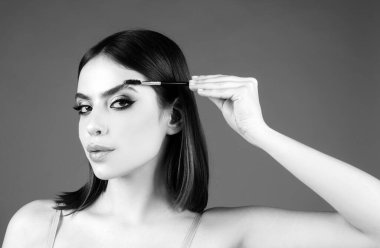 Modellik yapan kaşlar, güzel yüzlü büyüleyici bir bayan, sağlıklı ve temiz bir cilt, elinde fırça ve kaşlarını boyuyor. Mükemmel kaşları olan güzel bir kadın gözü.