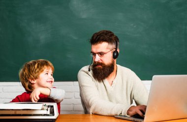 Erkek öğretmen okul öncesi çocukla oynuyor. Okula geri dön. Ders. İnsan çocuğa öğretir. Baba ve oğul birlikte. Sınıfta masabaşında okuyan öğrencilere yardım eden öğretmen.