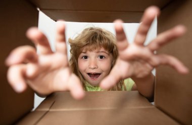 8 yaşında mutlu bir çocuk, karton kutuda, internet mağazasından paketleri açıyor. Çocuk müşteriler hızlı teslimat hizmetinden memnun. Çocuk açılış paketi. Çocuk, hediyesini el ile aç.