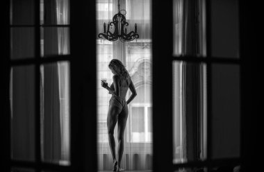 Yatak odasında panoramik pencereli güzel kadınlar. Evde ya da otel odasında yatakta tasasız kadın modeller. Sabah serinliği