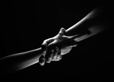İki eğilim ve iki eğilim. Bir arkadaşa yardım ediyorum. Kurtarmak ya da el hareketlerine yardım etmek. Kurtuluş kavramı. Kurtarma sırasında iki güçlü insanın elleri, yardım edin. Siyah arkaplanda izole