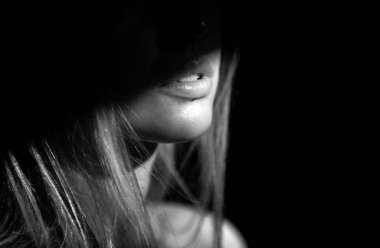 Stüdyoda poz veren genç bir kadın. Dudaklarında ışık ve gölge. Yüzünde siyah ışık olan güzel bir kadının moda portresi.