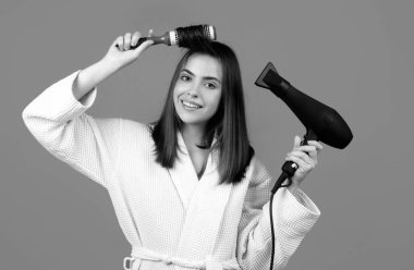 Saçını tarayan bir kadın. Saç fırçalayan taraklı ve saç kurutma makineli kadın modelin portresi. Saç kurutma makinesi, saç fırçası, saç bakımı ve güzellik.
