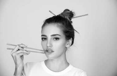 Yemek çubuklarıyla dudak karıştıran seksi, şehvetli bir kadın. Sushi reklamı için seksi bir ağız. Stüdyo izole edilmiş portre