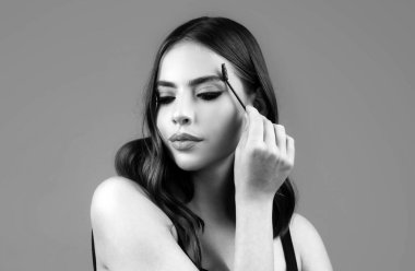 Güzellik salonunda fırçayla kaşlarını tarıyor. Uzun kirpikleri ve kalın kaşları olan seksi bir kadın. Mikro patinaj, modelleme kaşları