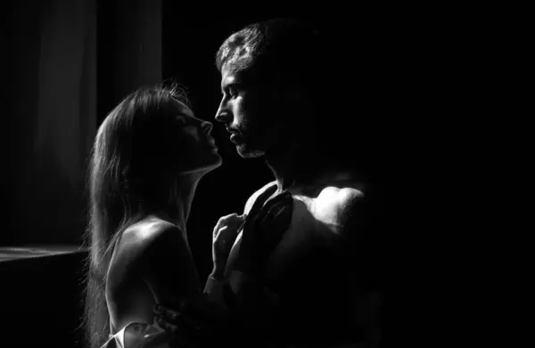 男は抱擁し 官能的な女性にキスしようとする 黒を背景に寝室でキスするカップルを愛しています バレンタインデーの本当の愛 — ストック写真