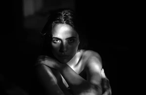 Girl face in shadow. Sexy alluring woman, sensual young model looking seduce on black studio. Fashion portrait of elegant woman in shadow, glamor light