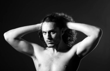 Çıplak gövdeli ve kıvırcık saçlı bir adam. Gri arka plan fotokopi alanında izole edilmiş mükemmel kıvırcık saçlı çekici, kaslı esmer adamın yakın portresi.