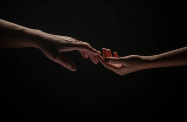 Parmaklarınla romantik dokunuş, aşkım. İki el birbirini gerer, siyah arka plan. Birbirine aşık çiftler, yaklaşın. Yardım eli, destek, arkadaşlık. Şefkat, şefkat dokunuşu
