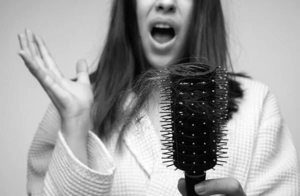 Sad girl with damaged hair. Hair loss problem treatment. Portrait of woman with a comb and problem hair