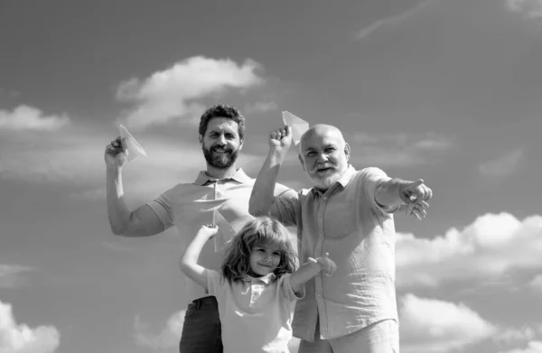 Three different generations ages grandfather father and child son playing with toy plane outdoors. Family adventure, imagination, innovation and inspiration