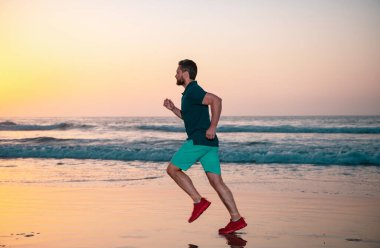 Yaz plajında koşan sporcu adam, renkli günbatımı gökyüzü