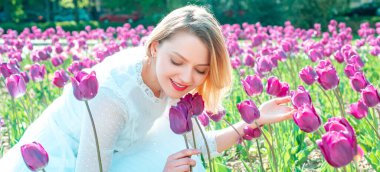 Lale pankartlı bahar kadını. Genç bayan lale tarlalarında dinleniyor.