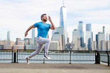 Kaçak. Sokakta koşan bir adam. Olgun koşucu ve spor modelleri New York 'ta Manhattan yakınlarında antrenman yapıyor. Milenyum sporcusu dışarıda spor yaparken koşuyor.