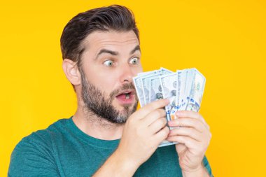 Sarı stüdyoda para tutan şanslı adamın portresi. Büyük şans, afiş. Dolar nakit para konsepti. Nakit para kazanmak için sevinir, şanslı para. Nakit parası olan bir adam. Finansal şans ve başarı
