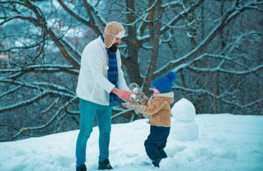 Mutlu baba ve oğul kış Noel zamanı oynarlar. Baba ve oğlu dışarıda oynuyorlar. Mutlu kış zamanı. Dost aile kavramı