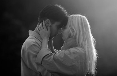 Şehvetli aşıklar gün batımında sarılıp öpüşüyorlar. Genç şehvetli kız arkadaşı, erkek arkadaşından tutkulu bir öpücük aldığı için mutlu. Yakışıklı genç adam kadınını kucaklıyor ve öpüyor.