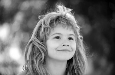 Bahar parkında küçük sevimli bir çocuğun yakın plan portresi. Mutlu çocuk dışarıda eğleniyor. Çocukluk kavramı