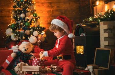 Noel hediyesi tutan komik çocuk. Noel ağacının yanında şirin bir çocuk. Kış Noel heyecanı. Yeni yıl Noel konsepti