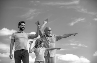 Büyükbaba ve oğul gökyüzünde oyuncak uçakla oynuyorlar. Mutlu bir aile. Üç erkek nesli. Mutlu çocukluk