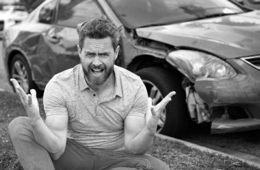 Stresli sürücü yolda kırık arabanın yanında oturuyor.