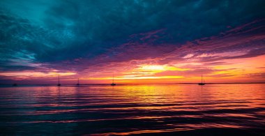 Okyanusta gün batımı ya da gün doğumu, doğa manzarası arka plan, gökyüzünde parlayan güneşe uçan pembe bulutlar. Akşam ya da sabah manzarası