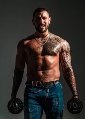 Güçlü yakışıklı sporcu halter kaldırıyor ve halterle kaslarını çalıştırıyor.